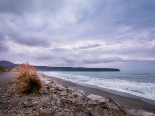 The windy beach at Bruce Bay with the sunset sky in the background, located on the West Coast of New Zealand near Haast Highway, at the Tasman Sea.