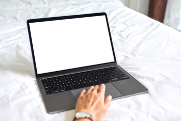 Mockup image of a woman using and typing on laptop with blank white desktop screen keyboard on the bed