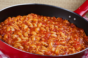 Goulash and noddles cooking in a red skillet