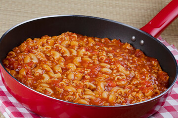 Goulash and noddles cooking in a red skillet