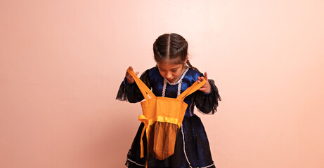 little girl dressed as a witch holding an orange bag