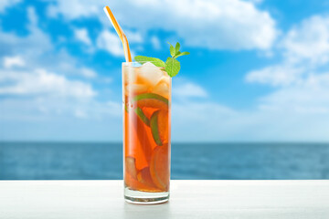 Glass of tasty cold ice tea on table at sea resort