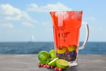 Jug of tasty cold tea on table at sea resort