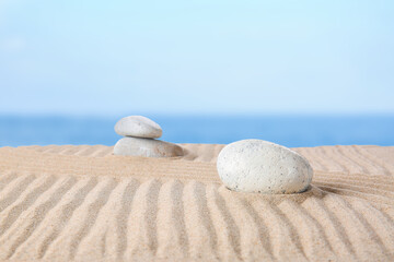 Fototapeta na wymiar Stones on sand with lines outdoors. Zen concept