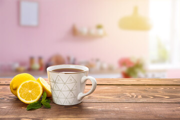 Cup of tasty tea with mint and lemon on wooden table in kitchen