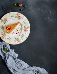 Sweet homemade layered honey cake on a black textured table