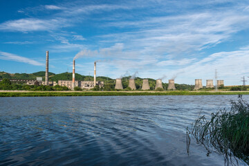 Fototapeta premium Hydro-electric station on the river bank and blue sky with clouds