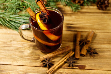 Christmas mulled wine with spices and fir tree branches and cones on wooden table