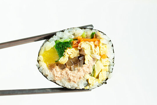 Korean roll gimbap and chopsticks on white background close-up.