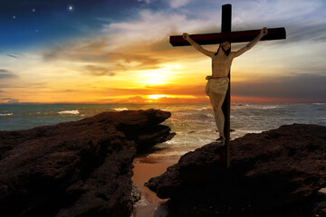 Crucifix crucifixion Jesus Christ on the rocks by the sea at sunset.