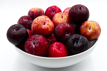 Naklejka na ściany i meble Fresh plums in a bowl, isolated on white background. 
