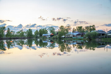 Reflection of the village in the pond in the evening