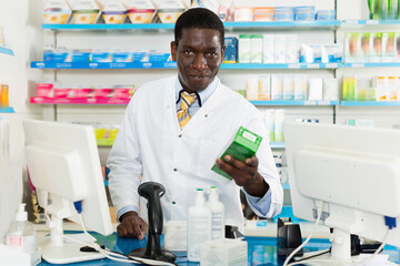 Portrait of experienced positive smiling male pharmacist counseling about medicines in pharmacy