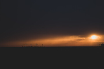 Tower cranes and buildings on horizon with evening sky, soft focus. Sunset over city. Construction with scenic evening sky and clouds above. Picturesque cityscape in evening haze. 