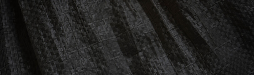 Abstract black background. Black and white background. Crumpled fabric texture. Polypropylene. The texture of the rough surface of artificial fabric. Black grunge texture background.