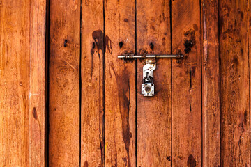 A closed wooden brown door from a rural place in India.