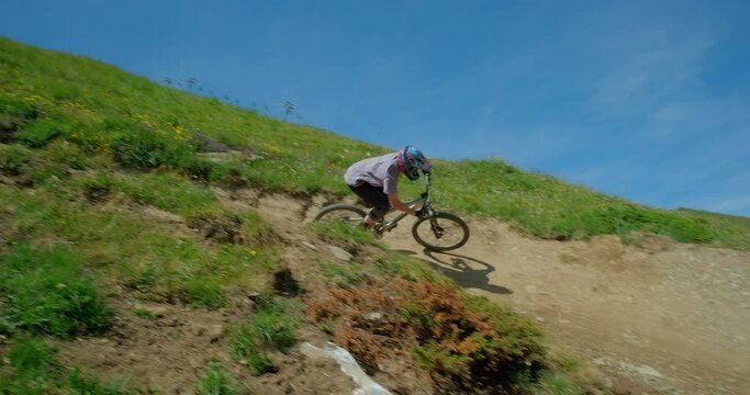 A mountain biker riding around a berm (steep banked turn) on a downhill mountain bike course in Tignes, French Alps.