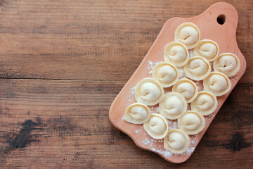 Homemade dumplings stuffed with meat on a wooden board. Top view, copy space