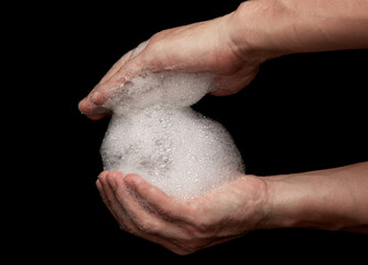 Naklejka premium hands in white foam from soap on a black background