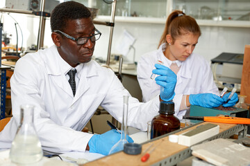 Serious man lab scientist in glasses working with reagents and test tubes in laboratory