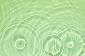 de-focused. Closeup of mint green transparent clear calm water surface texture with splashes and bubbles. Trendy abstract summer nature background. Mint colored waves in sunlight. 