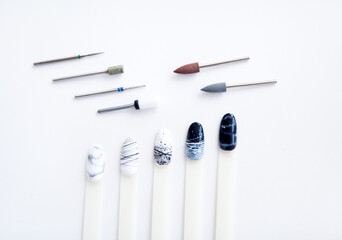 nail samples with black and white manicure design laid out in a line as a nail burs. polisher carbide and diamond burs