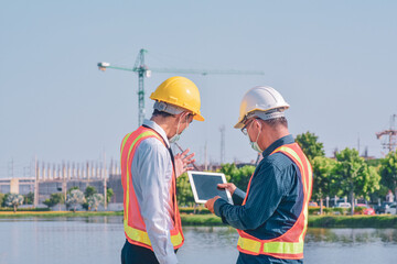 Businessman in medical mask talking on site construction by tablet technology