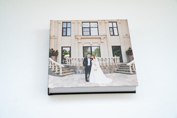 closed wedding photobook with thick pages on a white table. convenient, beautiful and long-lasting storage of photos from photo sessions. Russian names Artyom and Arina are written on the cover.