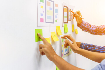 The team of website designers with the ux ui system are writing programs and laying the layer to determine the display style with the ux ui system within the front of the smartphone.