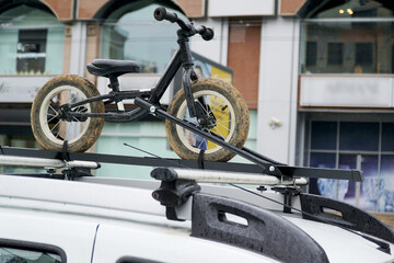  A children's bicycle without pedals is installed and fixed in the trunk on the roof of the car and...
