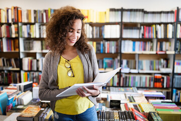 Portrait of happy mixed race college woman student at campus library