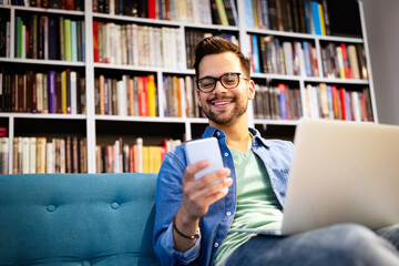 Cheerful smiling man talking on phone and working, studying on laptop