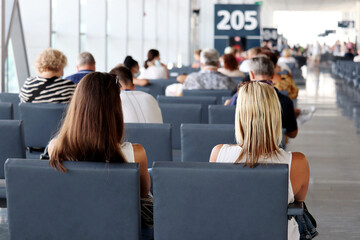 Passengers sitting in the airport terminal. People are waiting for their flight, travel concept