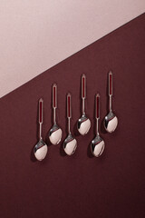 Set of six vintage silver dessert or tea spoons with red enamel details laying flat on a deep red...
