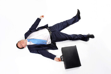 On floor lying down tired exhausted businessman holding a suitcase