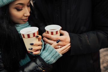 Close-up portrait of a couple holding a cups of hot beverage. Cropped shot.