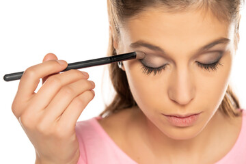 Portrait of young beautiful woman applying eyeshadow