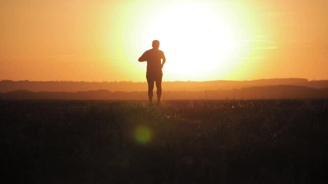 Running man silhouette in sunset time. Outdoor cross-country running. Athletic young man is running in the nature during golden sunset. Healthy lifestyle.