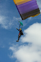 Woman skydiver under the parachute canopy is getting ready for landing.