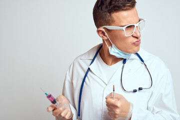 doctor in a medical gown with a stethoscope and glasses on a light background cropped view portrait