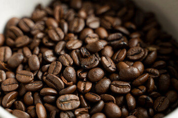 Bowl filled of fresh arabica or robusta coffee beans on a wooden table.