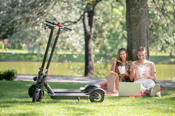 Young couple eating lunch under the tree and looking relaxed