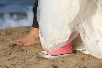 Wedding. Bare feet of loving men and women on a sandy beach by the sea