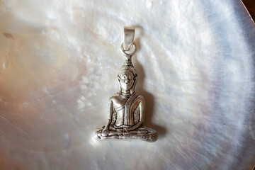 Beautiful silver Buddha pendant jewelry on pearly white shell background