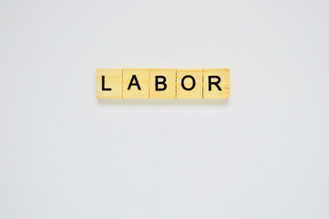 Word labor. Wooden blocks with lettering on top of white background. Top view of wooden blocks with letters on white surface