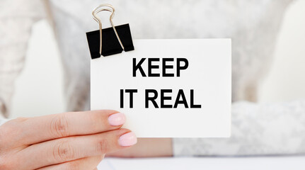 KEEP IT REAL inscription on the business card, which is held in front of the girl.