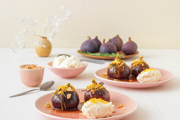 Caramelised figs with balsamic vinegar, rosemary, almonds and cottage cheese. Slow roasted homemade fruit dessert. White wooden table background. No people. Gordon Ramsey recipe.