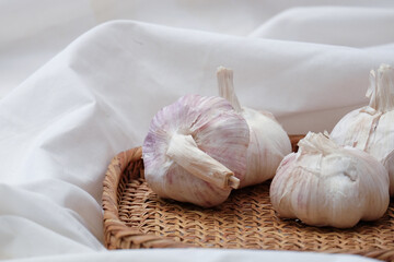 Garlic in a vintage wood plate on a white cloth background