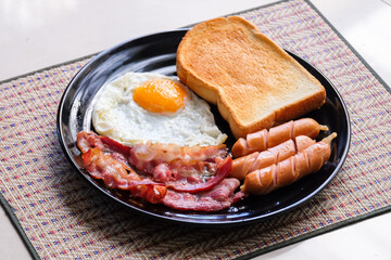 fried eggs with bacon, sausages and toasts. fried eggs with bacon, sausages and toasts on black plate