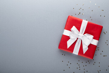 Gift or present box and stars confetti on color table top view. Flat lay composition for birthday, mother day or wedding.